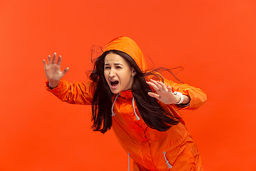 Image showing The young girl posing at studio in autumn jacket isolated on red