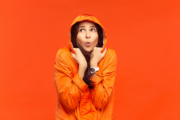 Image showing The young girl posing at studio in autumn jacket isolated on red