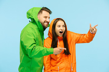 Image showing The young surprised couplel posing at studio in autumn jackets isolated on blue