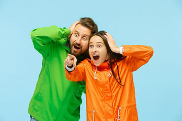 Image showing The young surprised couplel posing at studio in autumn jackets isolated on blue