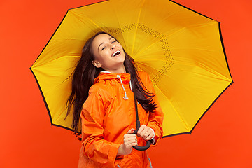 Image showing The young girl posing at studio in autumn jacket isolated on red