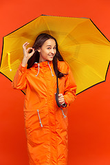 Image showing The young girl posing at studio in autumn jacket isolated on red