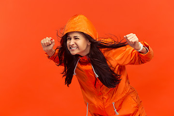 Image showing The young girl posing at studio in autumn jacket isolated on red