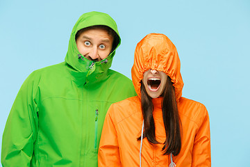 Image showing The young surprised couplel posing at studio in autumn jackets isolated on blue