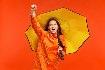 Image showing The young girl posing at studio in autumn jacket isolated on red