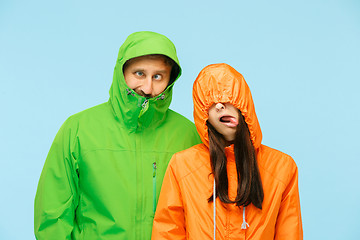 Image showing The young couplel posing at studio in autumn jackets isolated on blue