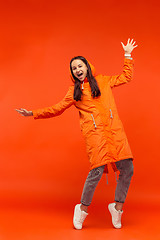 Image showing The young girl posing at studio in autumn jacket isolated on red