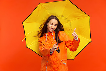 Image showing The young girl posing at studio in autumn jacket isolated on red