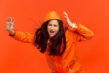 Image showing The young girl posing at studio in autumn jacket isolated on red