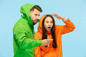 Image showing The young surprised couplel posing at studio in autumn jackets isolated on blue