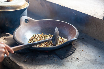 Image showing Person roasting fresh coffee beans in a skillet