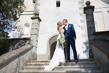 Image showing The Kiss. Bride and groom kisses tenderly on a staircase in front of a small local church.