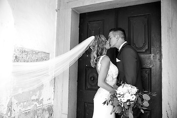 Image showing The Kiss. Bride and groom kisses tenderly in front of church portal.