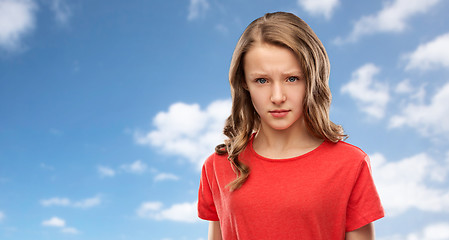 Image showing sad or angry teenage girl in red t-shirt over sky