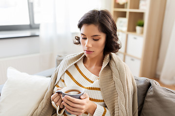 Image showing sad sick young woman drinking hot tea at home