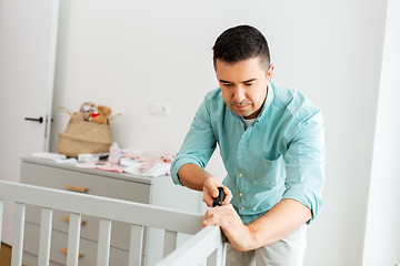 Image showing happy father with screwdriver assembling baby bed