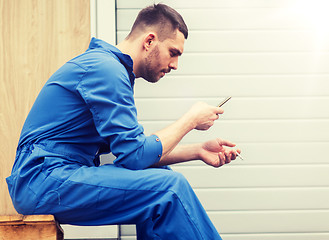 Image showing auto mechanic smoking cigarette at car workshop