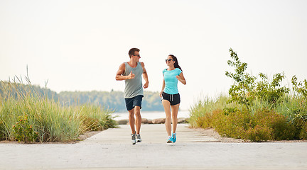 Image showing couple in sports clothes running along beach path