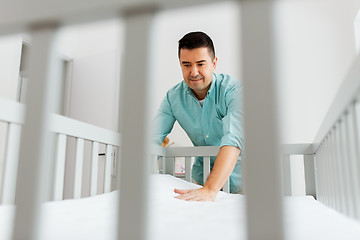 Image showing father arranging baby bed with mattress at home