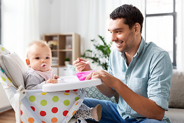 Image showing father feeding happy baby in highchair at home