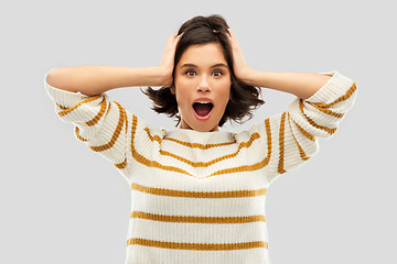 Image showing impressed woman in pullover holding to her head