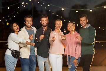 Image showing happy friends with sparklers at rooftop party