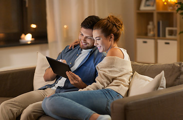 Image showing happy couple using tablet pc at home in evening