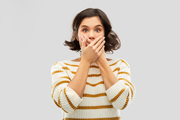 Image showing shocked young woman covering her mouth by hands