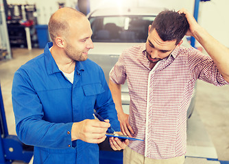 Image showing auto mechanic with clipboard and man at car shop