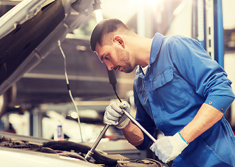 Image showing mechanic man with wrench repairing car at workshop