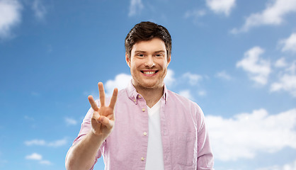 Image showing young man showing three fingers over sky