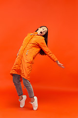 Image showing The young girl posing at studio in autumn jacket isolated on red