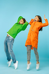 Image showing The young surprised couplel posing at studio in autumn jackets isolated on blue