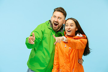 Image showing The young surprised couplel posing at studio in autumn jackets isolated on blue