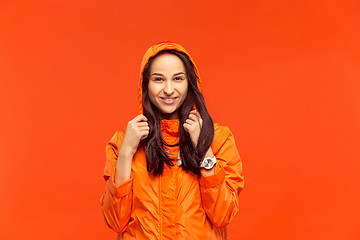 Image showing The young girl posing at studio in autumn jacket isolated on red