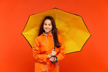 Image showing The young girl posing at studio in autumn jacket isolated on red