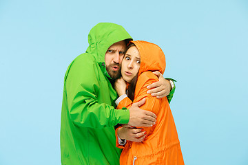 Image showing The young couplel posing at studio in autumn jackets isolated on blue