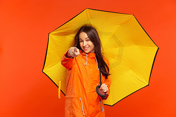 Image showing The young girl posing at studio in autumn jacket isolated on red