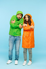 Image showing The young couplel posing at studio in autumn jackets isolated on blue