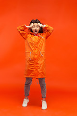 Image showing The young girl posing at studio in autumn jacket isolated on red