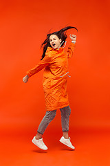 Image showing The young girl posing at studio in autumn jacket isolated on red