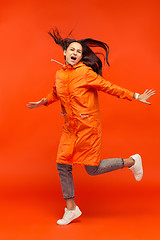 Image showing The young girl posing at studio in autumn jacket isolated on red