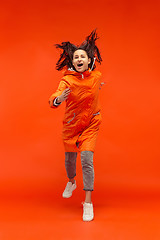 Image showing The young girl posing at studio in autumn jacket isolated on red