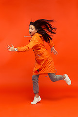 Image showing The young girl posing at studio in autumn jacket isolated on red