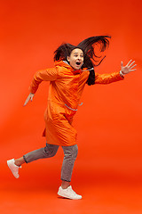 Image showing The young girl posing at studio in autumn jacket isolated on red