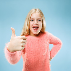 Image showing The happy teen girl standing and smiling against blue background.