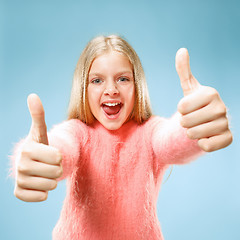 Image showing The happy teen girl standing and smiling against blue background.