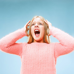 Image showing Isolated on blue young casual teen girl shouting at studio