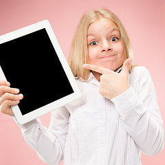 Image showing Little funny girl with tablet on pink background