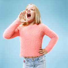 Image showing Isolated on blue young casual teen girl shouting at studio